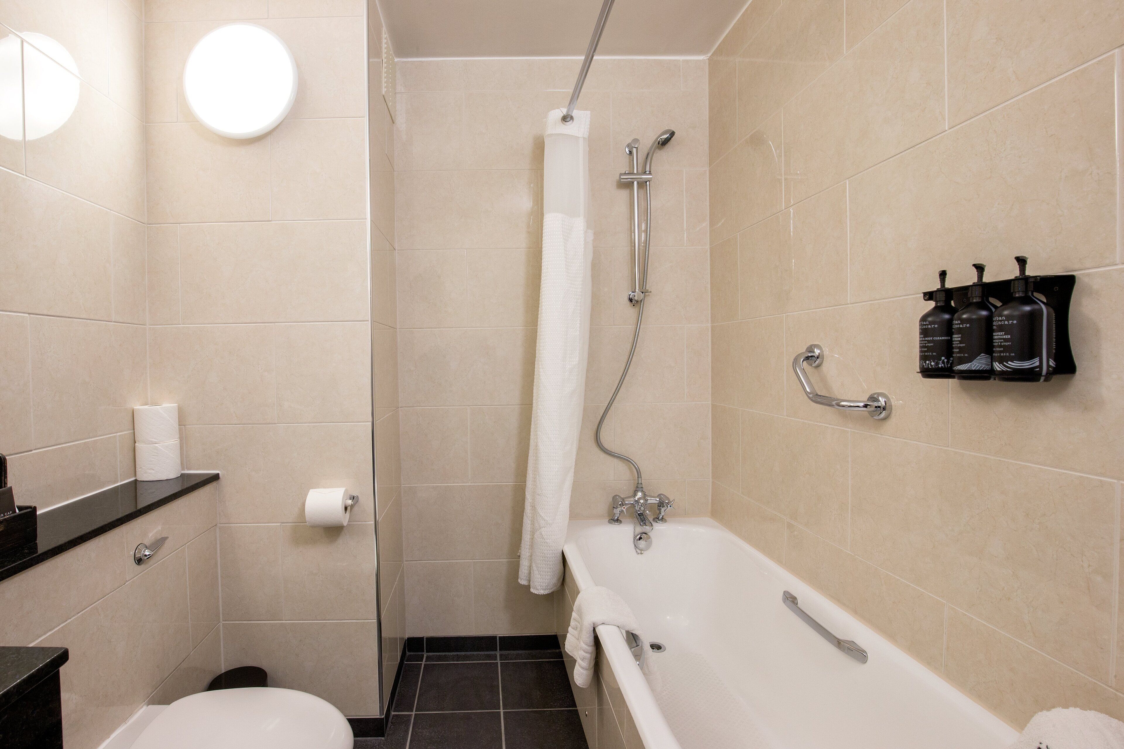 A bathroom with a toilet, sink, bathtub, shower, and towel rack.