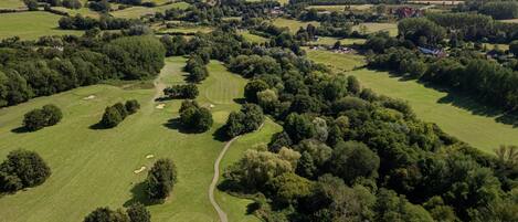 Vista aérea de un campo de golf con varios fairways, búnkeres de arena y grupos de árboles.