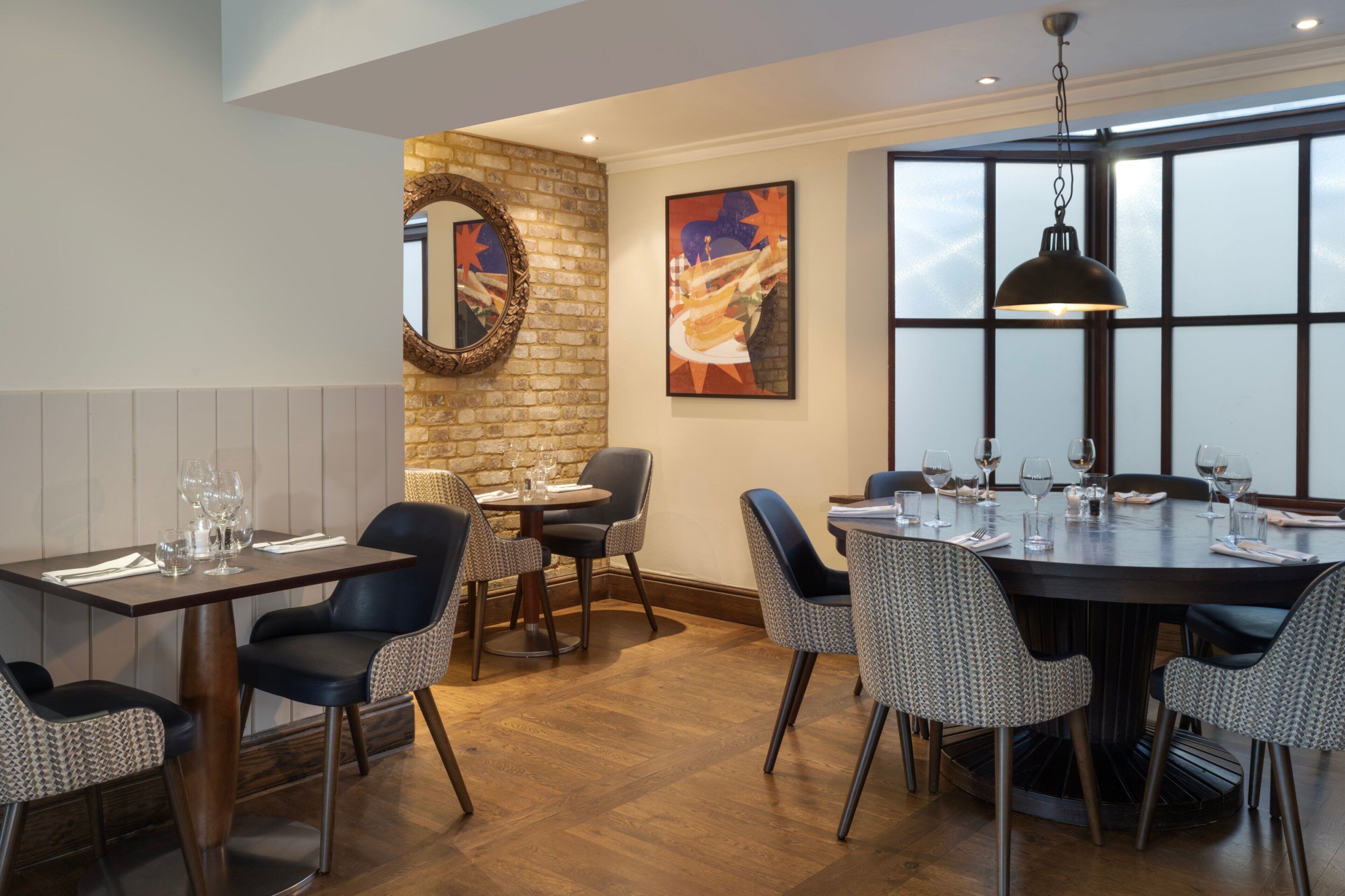 A dining area with a brick wall, a round table, and chairs.
