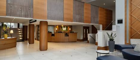 A spacious lobby with a reception desk, seating area, and a staircase.