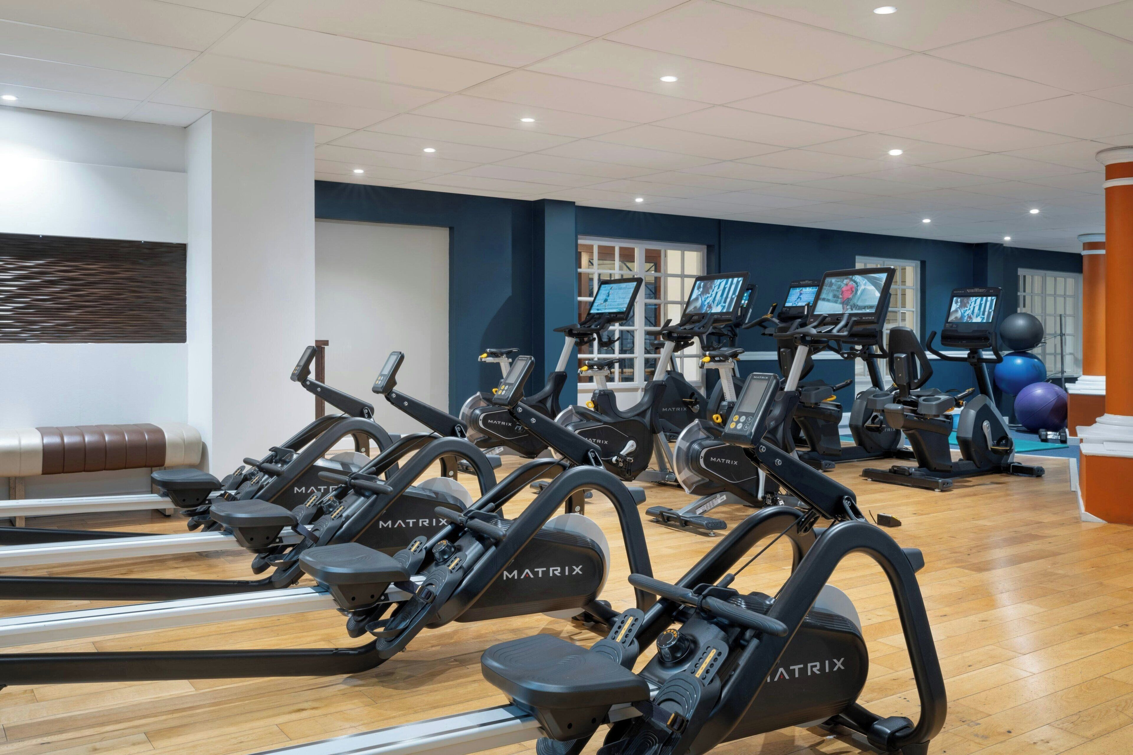 Una palestra con diverse tapis roulant, cyclette ed elastici per esercizi.