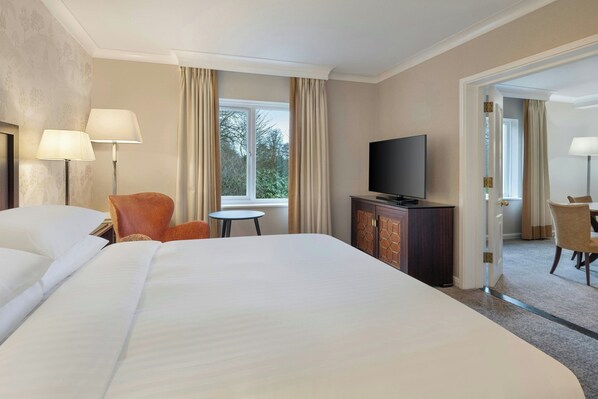 Una habitación de hotel con una cama grande, televisión, una mesita y una silla.