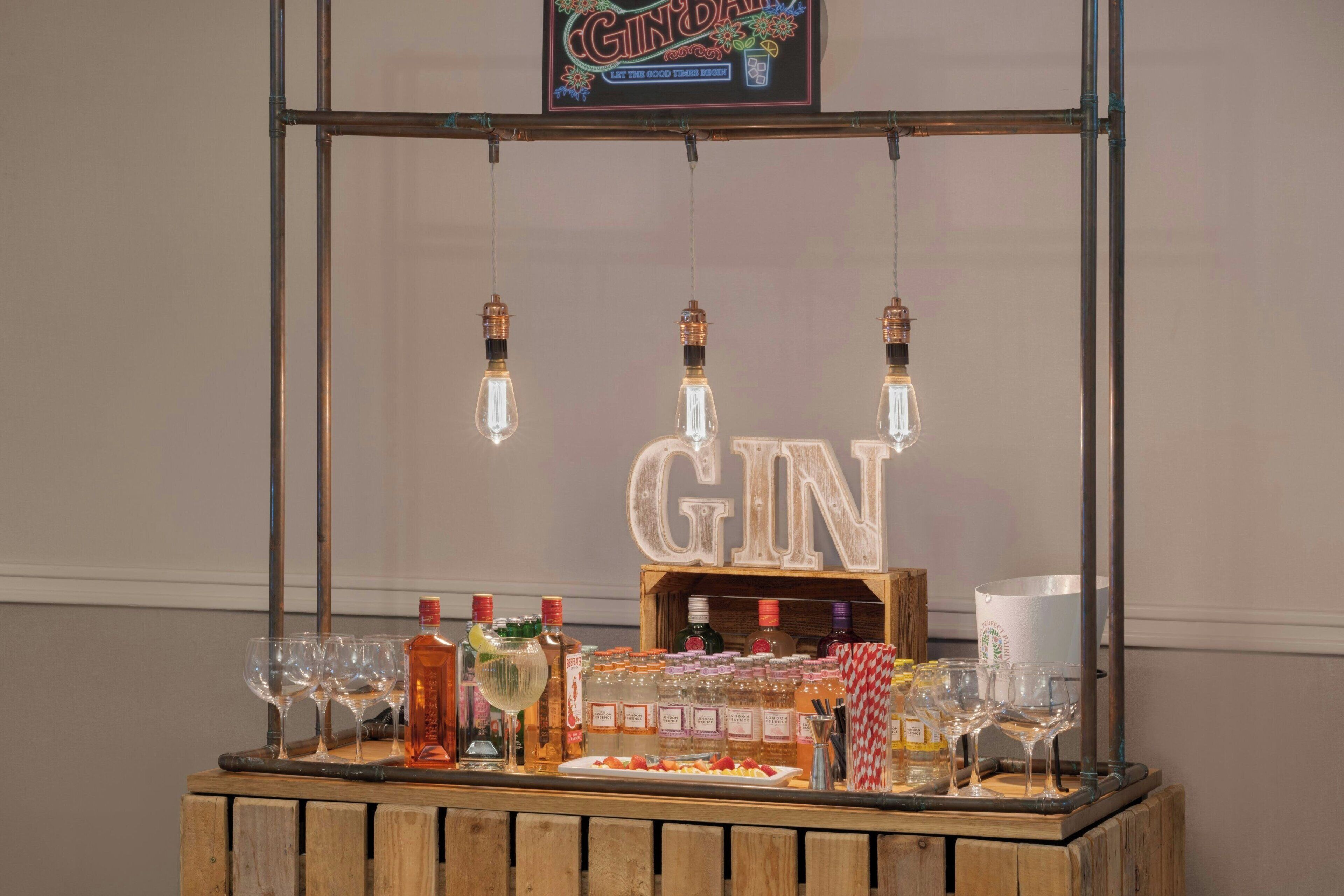 A gin bar setup with bottles, glasses, and a wooden counter.