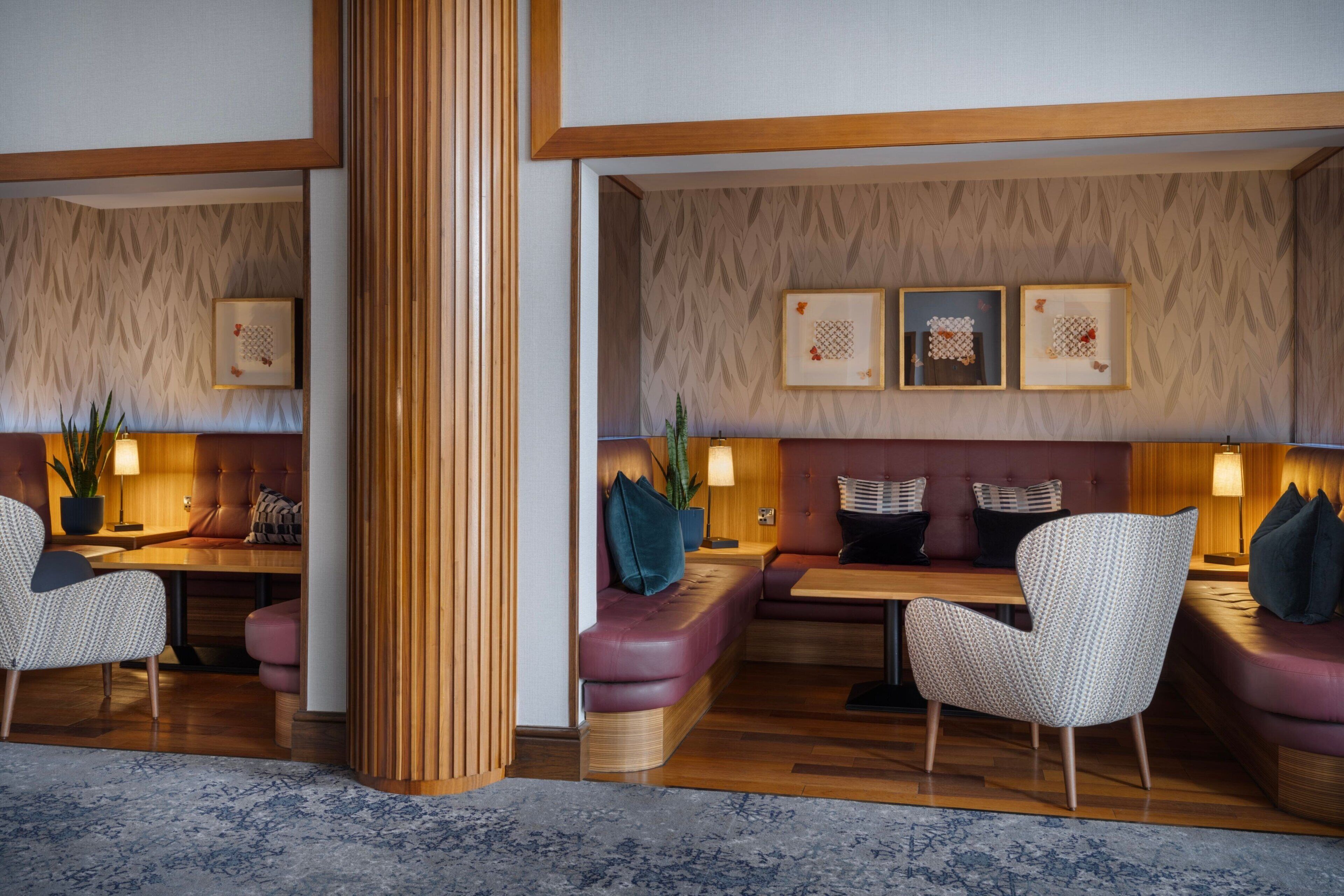 A modern lobby with wooden paneling, cushioned seating, and framed artwork on the walls.