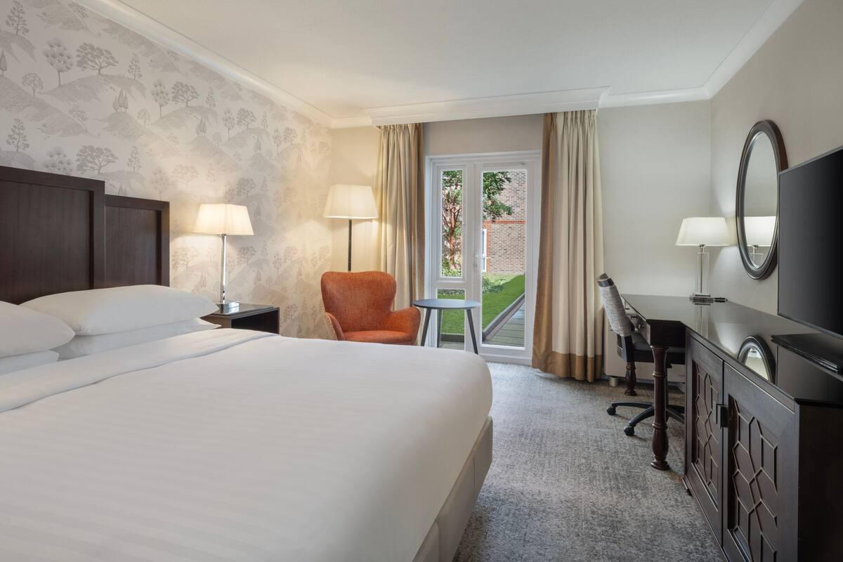 Une chambre d’hôtel avec un grand lit, un bureau, une chaise et un téléviseur.