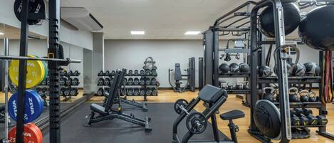 A gym with weightlifting equipment, dumbbells, and exercise machines.