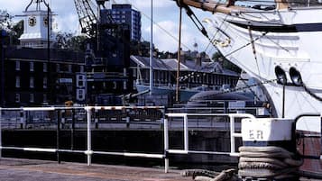 Ein historisches Kriegsschiff liegt im Hafen vor einem Hintergrund mit einem Glockenturm.