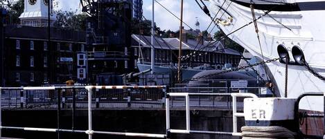 A historic warship docked at a harbor with a clock tower in the background.