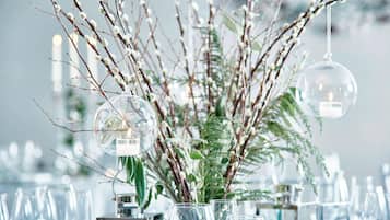 Una mesa dispuesta con cristalería transparente y un arreglo decorativo de ramas y follaje.
