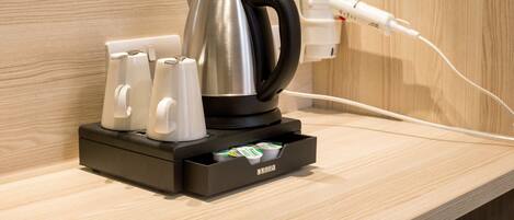 A coffee maker with four cups and a power outlet on a wooden countertop.