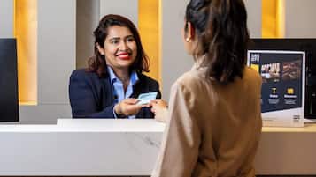 A hotel reception desk with a digital screen displaying amenities and a President Hotel sign.