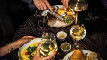 A dining table with plates of food, glasses of wine, and a menu.