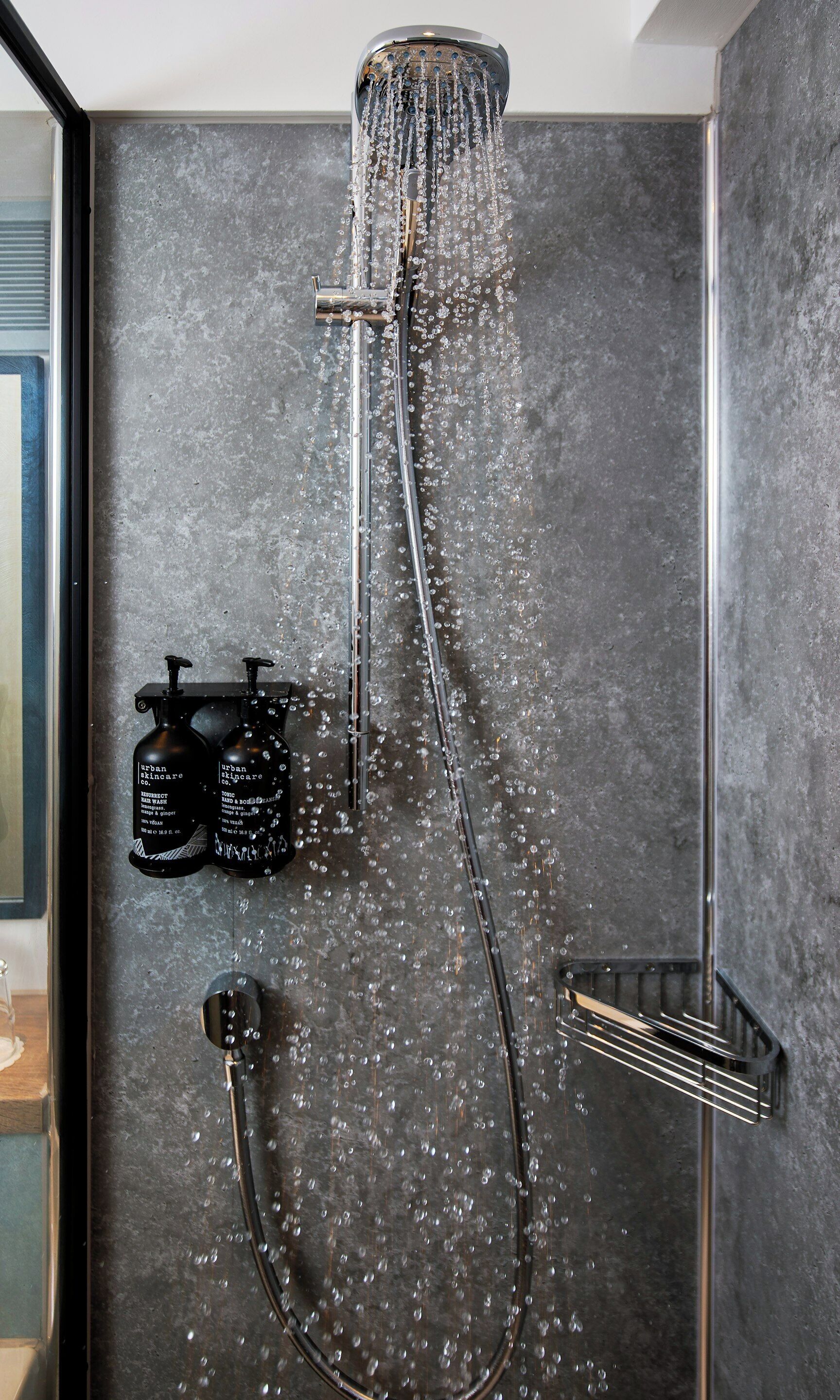 A modern shower with a rain showerhead, a handheld showerhead, and a handheld soap dispenser.