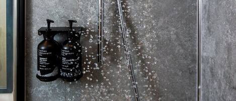 A modern shower with a rain showerhead, a handheld showerhead, and a handheld soap dispenser.