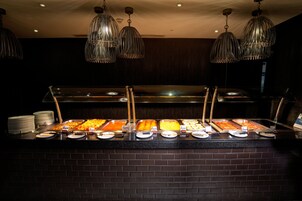 A buffet counter with various food options, a brick wall, and hanging metal light fixtures.