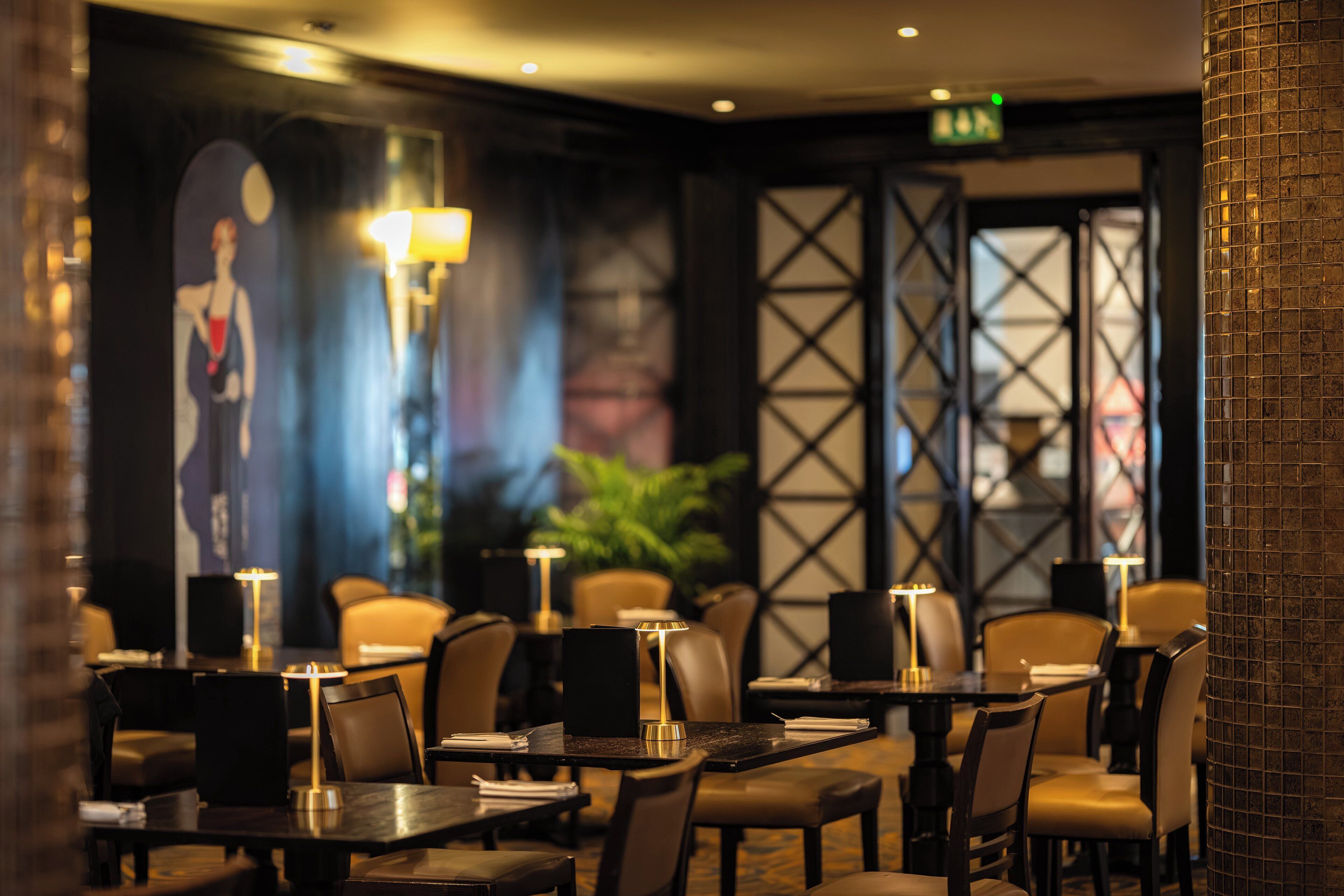A restaurant with tables and chairs, ambient lighting, and a decorative wall with a geometric pattern.