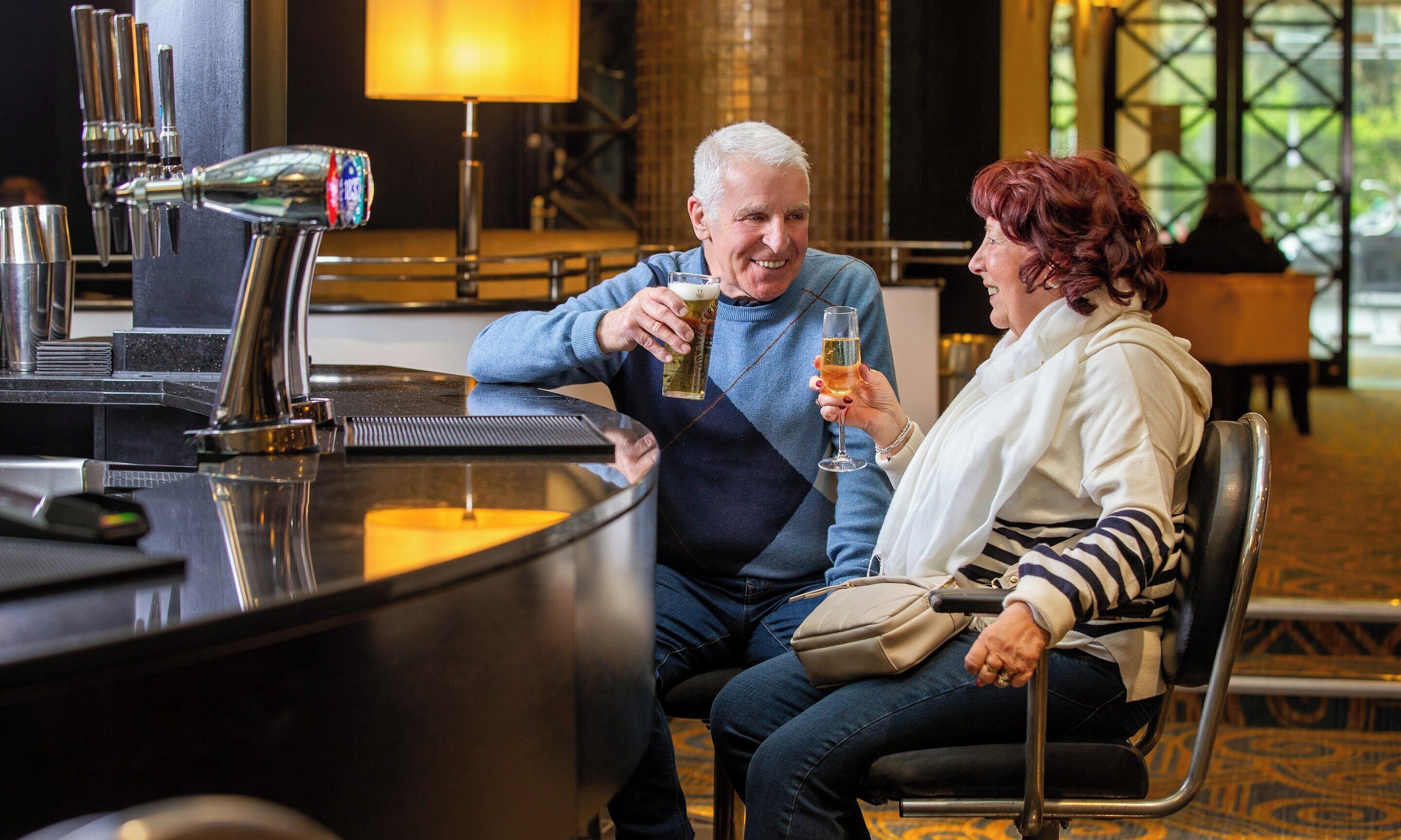Un homme et une femme sont assis au bar du hall d’un hôtel.