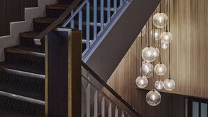 A staircase with wooden steps and a metal railing, leading to a landing with a hanging light fixture. - President Hotel (London)