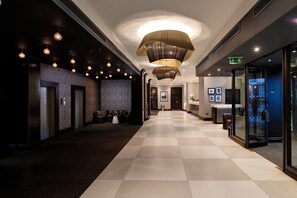 Experience the sleek lobby with a checkered floor, unique light fixture, and artwork-adorned walls.