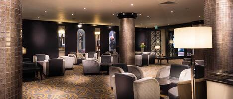 A lobby with seating areas, a patterned carpet, and a large pillar.