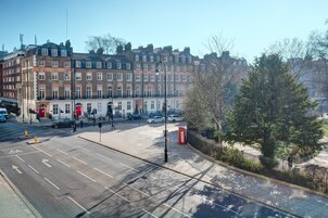 A street view with a row of terraced houses, a red telephone box, and a tree.
