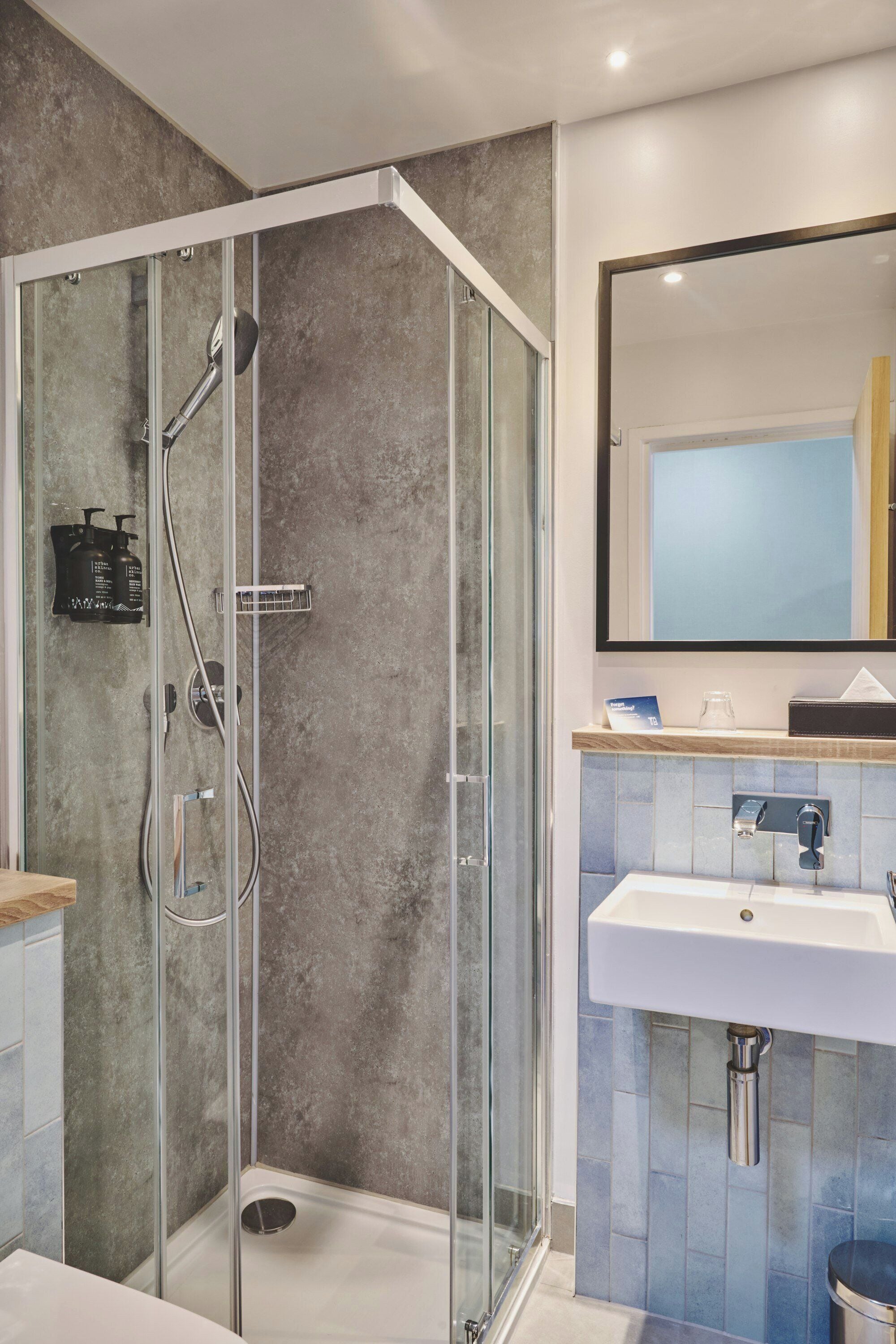 A modern bathroom with a glass-enclosed shower, a white sink, and a mirror above the sink.