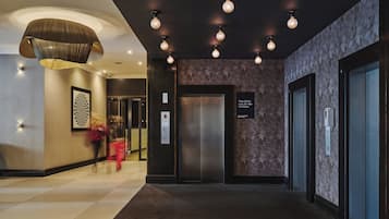 Eine Hotelhalle mit modernem Design, inklusive einer großen Chandelüster, einer Wand mit Musterung und einem Aufzug.