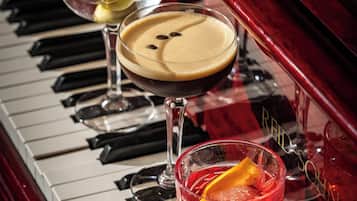 Een piano met drie glazen drank op de toetsen.