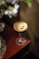 A cocktail in a martini glass on a wooden surface.