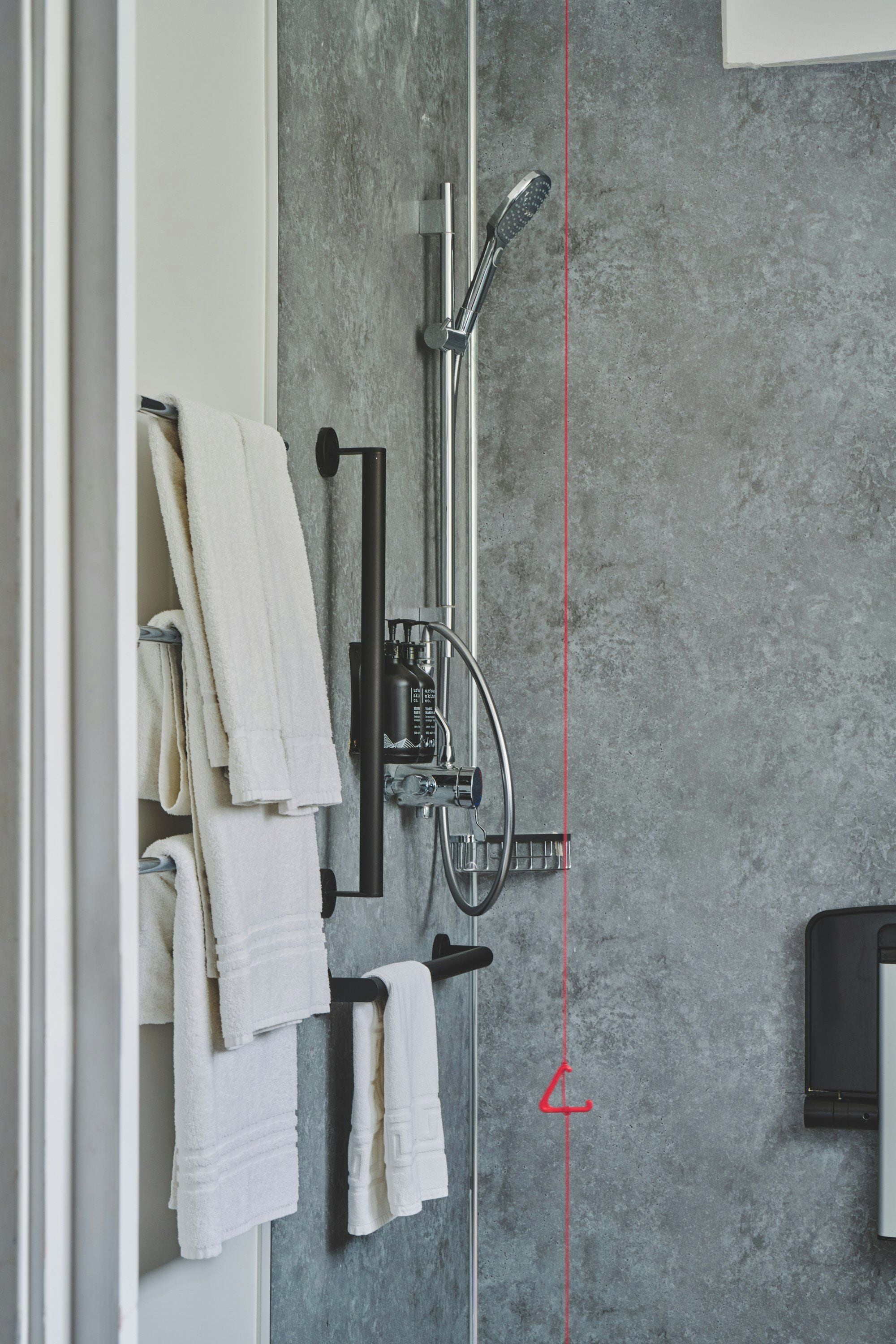 Une salle de bain avec une douche, un porte-serviettes et une ligne rouge sur le mur.