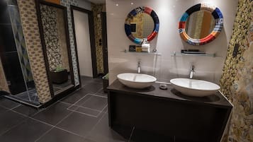 Ein modernes Badezimmer mit zwei großen Waschbecken, einer Duschkabine aus Glas und dekorativen Spiegeln.