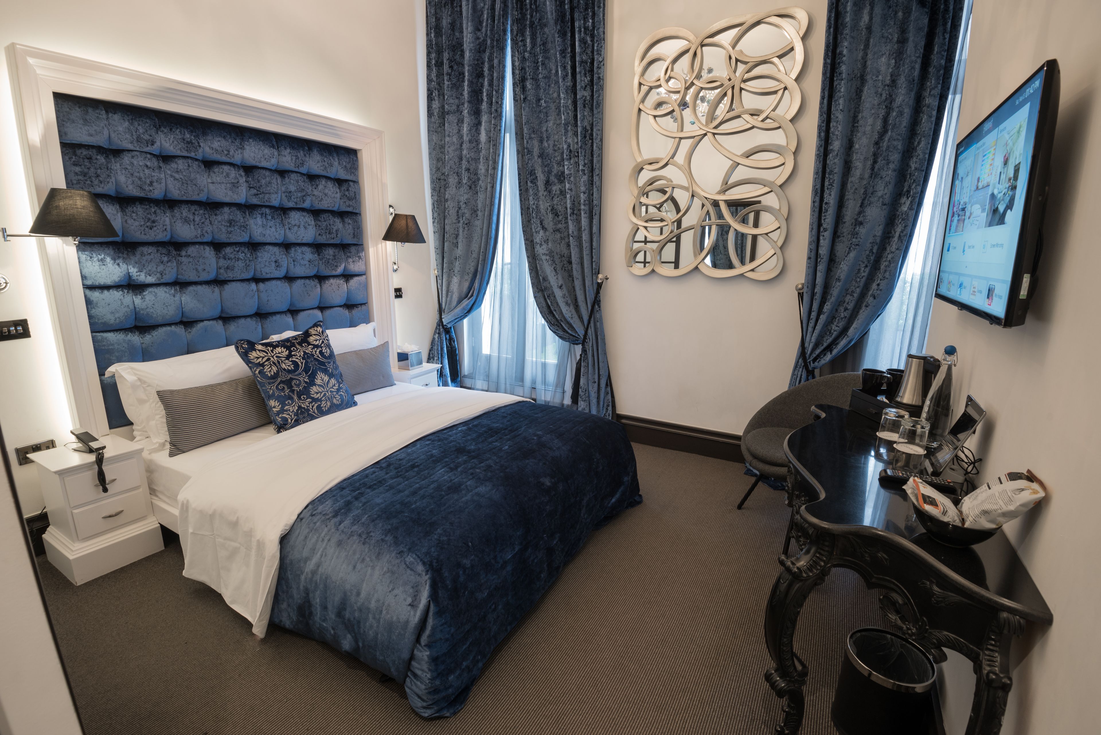 Een hotelkamer met een groot bed, een bureau, een televisie en een decoratief wandobject.