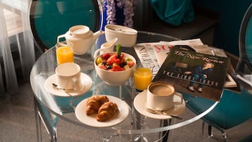 A breakfast table with croissants, fruit, coffee, and juice.
