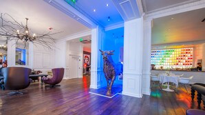 A modern interior with a wooden floor, a bull sculpture, and a colorful wall display. - The Exhibitionist Hotel (London)