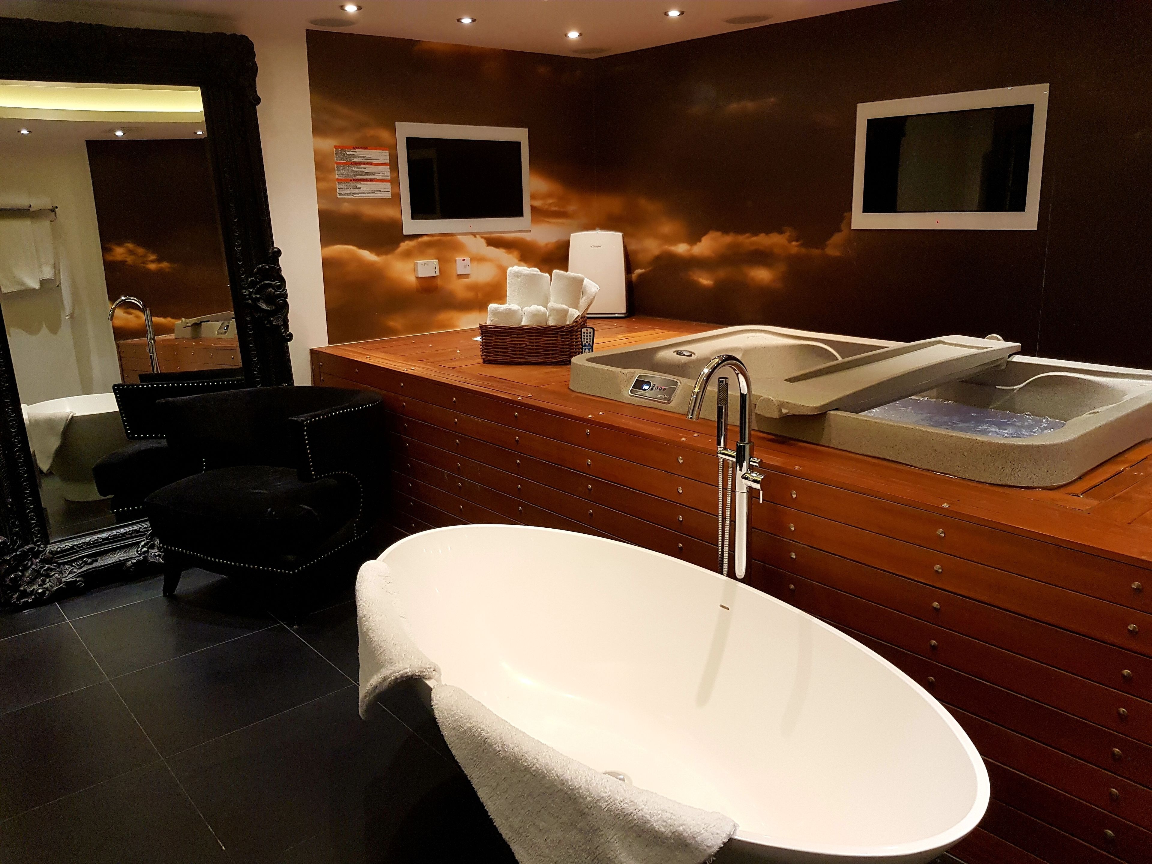 Un baño moderno con una bañera independiente, un mueble de tocador de madera con un lavabo y un espejo.