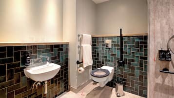 A modern bathroom with a white sink, a toilet, and a shower area.