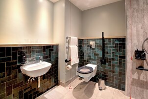 A modern bathroom with a white sink, a toilet, and a shower area.