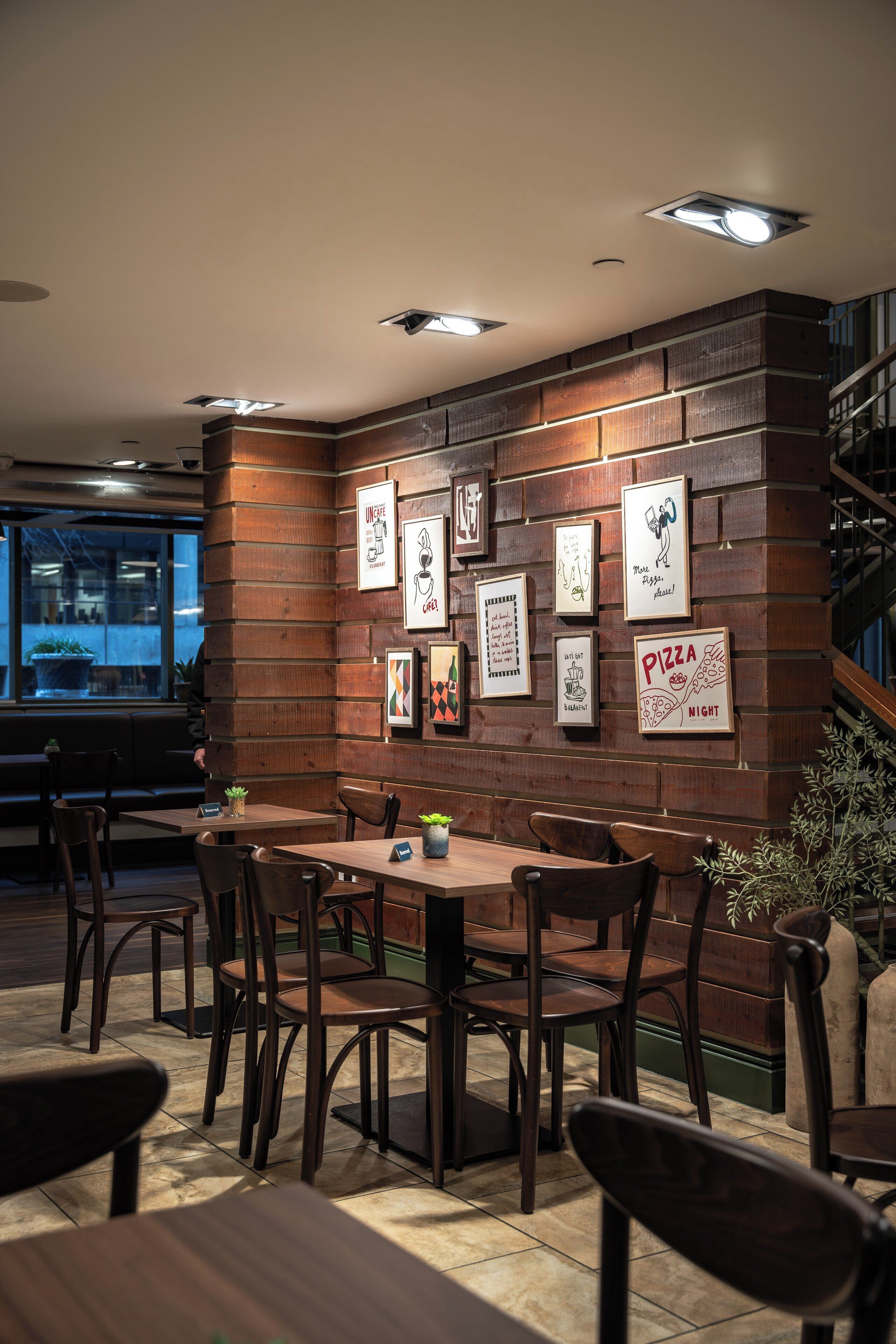 A restaurant with a wooden wall, framed artwork, and a seating area with tables and chairs.