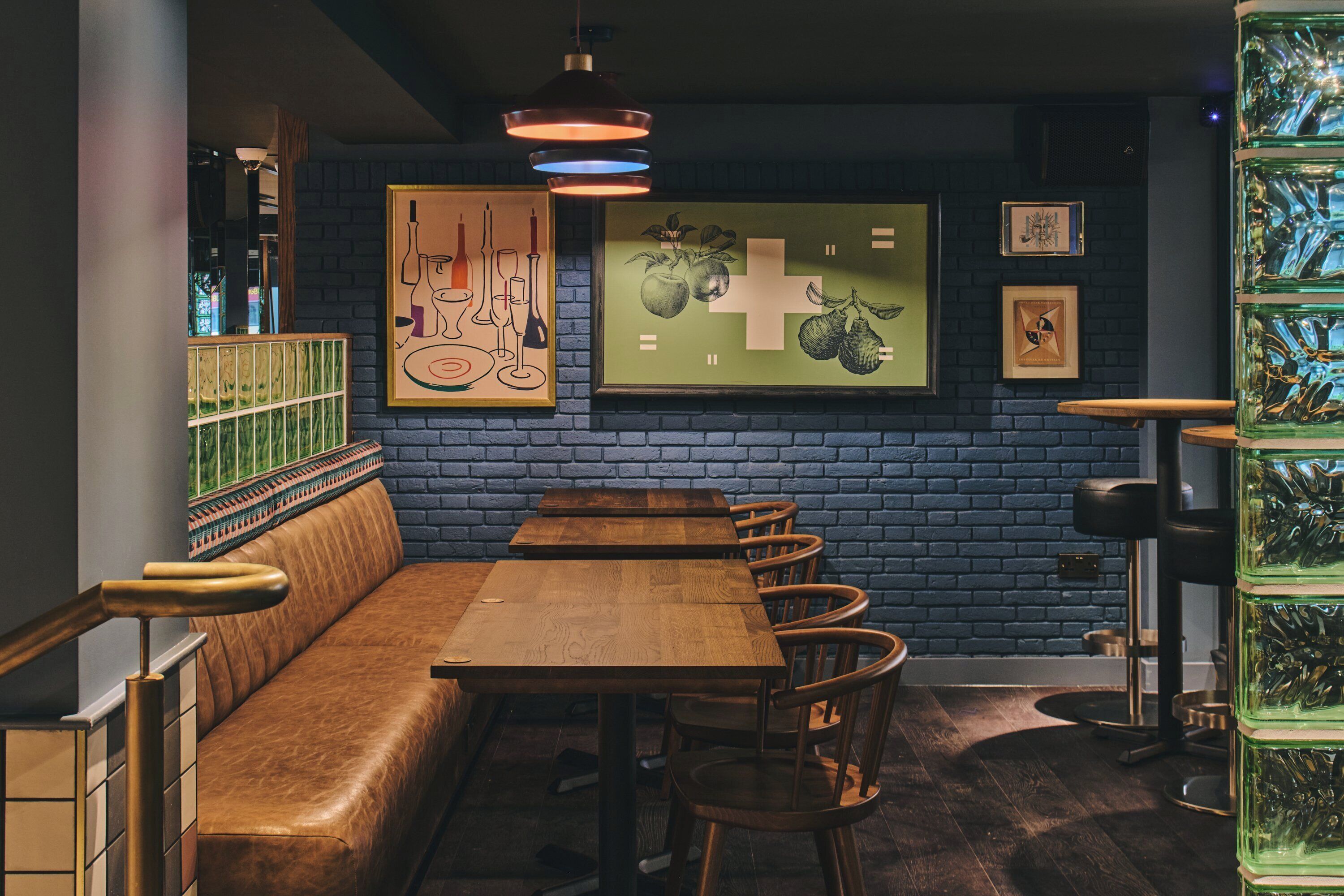 Un restaurante con mesas y bancos de madera, pared de ladrillo y obras de arte enmarcadas.