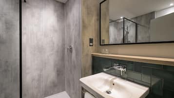 A modern bathroom with a large mirror, a white sink, and a shower area.