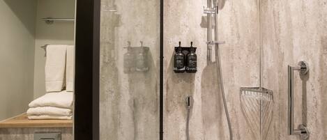 Une salle de bain moderne avec une douche à parois de verre, un porte-serviettes et deux bouteilles de shampoing.