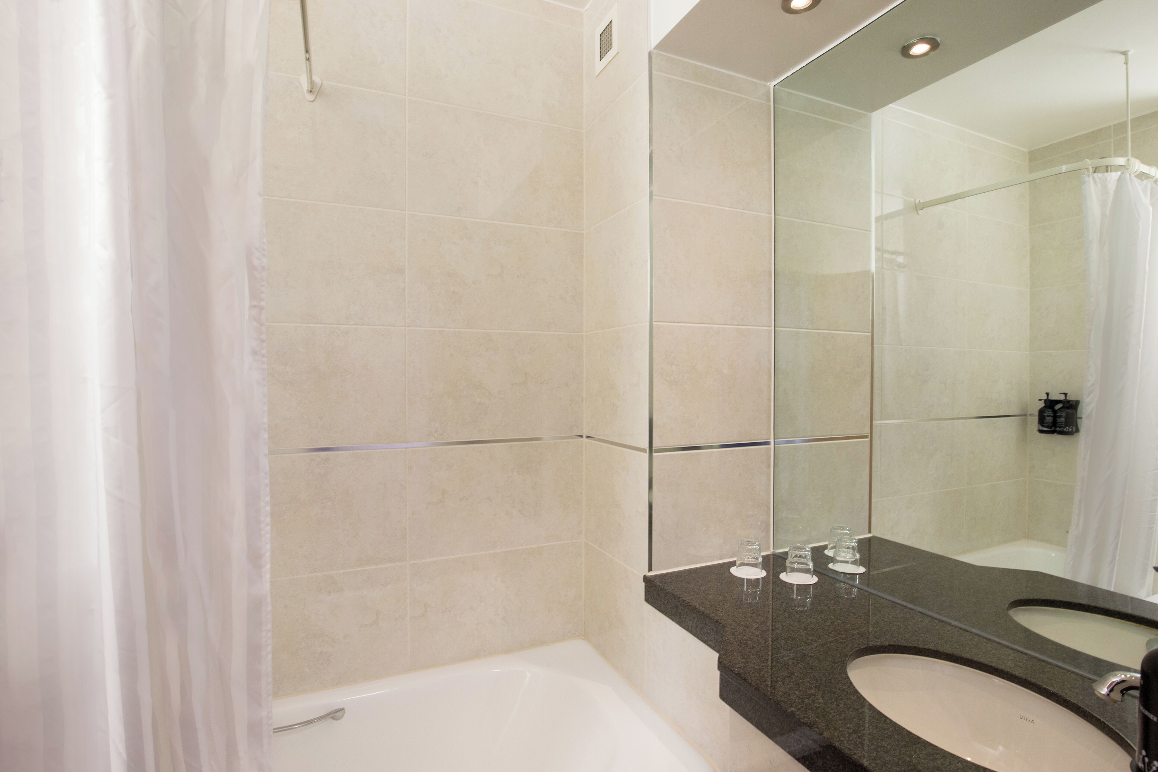 Un bagno moderno con una vasca, uno specchio grande e un mobile lavabo.