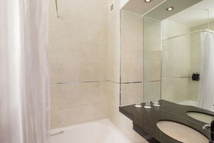 Un bagno moderno con una vasca, uno specchio grande e un mobile lavabo.
