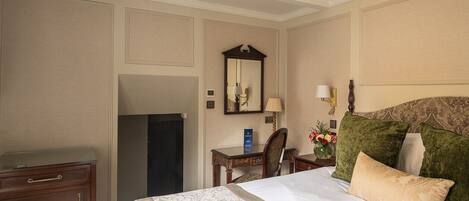 A hotel room with a bed, a desk, a chair, a dresser, a mirror, and a chandelier.