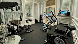 A gym with treadmills, a rowing machine, and weightlifting equipment.
