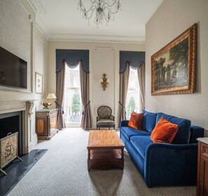 Un salon spacieux avec un canapé bleu, une table basse en bois, une cheminée et un grand tableau accroché au mur.
