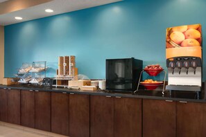 A breakfast bar with a juice dispenser, a coffee maker, and a fruit bowl. - Baymont by Wyndham Tulsa (Tulsa)