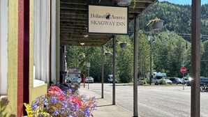 The exterior of Holland America Skagway Inn with a covered outdoor area, hanging planters, and a sign indicating the name. -  Holland America Skagway Inn (Skagway)