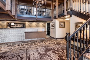A spacious lobby with a high ceiling, a reception desk, and a staircase leading to an upper level. -  Holland America Skagway Inn (Skagway)