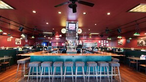 A bar area with a central counter, multiple stools, and a ceiling fan. -  Holland America Skagway Inn (Skagway)